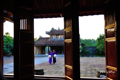 Hue girls in purple long dress and conical hat - Vietnam cycling tours