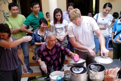Tourists learning how to make rolled rice pancake - Hanoi City Tour